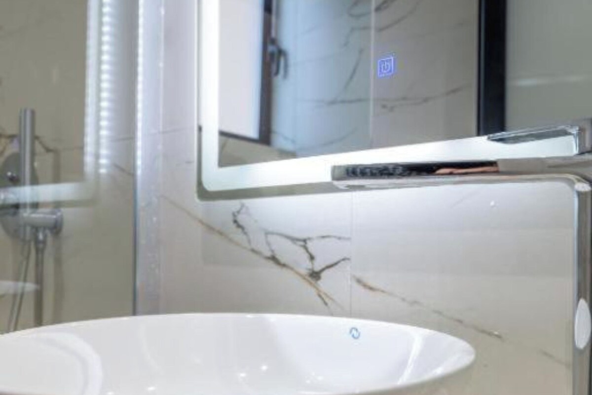 A bathroom with a white vessel sink, a glass shower enclosure, and a mirror above the sink.