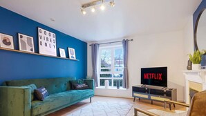 Ein Wohnzimmer mit einem grünen Sofa, einem Flachbildfernseher und einem Kamin.