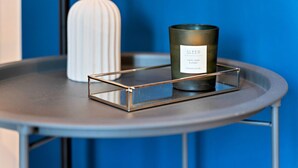 A round table with a metal tray holding a candle labeled "SLEEP" with scents of cassis, violet, and amber. - Stylish Apartment in City Centre with Free Parking (Chelmsford)