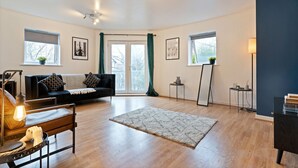 A modern living room with a sofa, a coffee table, a rug, and a lamp. - Stylish Apartment in City Centre with Free Parking (Chelmsford)