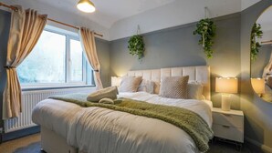 A bedroom with a bed, bedside tables, a mirror, and a window with curtains.
