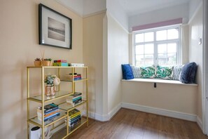 Una stanza con una libreria, una panca finestrata con cuscini e un quadro appeso al muro.