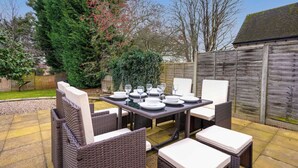 An outdoor patio with a table set for four, surrounded by wicker chairs.