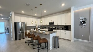 A modern kitchen with white cabinets, stainless steel appliances, and pendant lighting. - Last Minute Disney! Private Pool, Hot Tub, Game Room & Themed Bedrooms. Book Now! #110995 (Orlando)