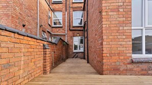 A narrow brick alleyway with wooden flooring leading to a door.