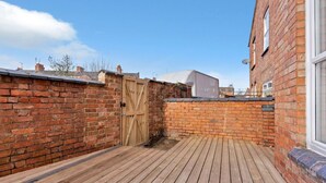 A wooden deck with a brick wall and a wooden gate.