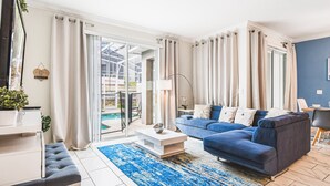 Ein modernes Wohnzimmer mit einem blauen Sofa, einem weißen Couchtisch und einem blau-weißen Teppich.