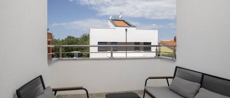 A balcony with a view of a building, a sofa, a table, and a chair.