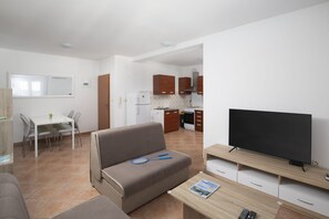 En moderne lejlighed med stue, spiseområde, tekøkken og TV.