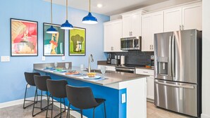 A modern kitchen with a central island, stainless steel appliances, and blue pendant lighting. - Last Minute Disney Getaway! Private Pool & Themed Bedrooms. Book Now! #110749 (Orlando)