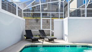 A pool area with two lounge chairs and a glass-enclosed structure. - Last Minute Disney Getaway! Private Pool & Themed Bedrooms. Book Now! #110749 (Orlando)