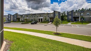 A modern apartment complex with multiple buildings, a parking lot, and a well-maintained lawn. - Last Minute Disney Getaway! Private Pool & Themed Bedrooms. Book Now! #110749 (Orlando)