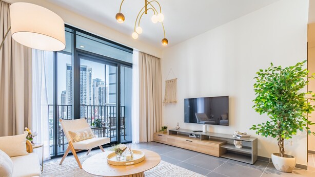A modern living room with a large TV, comfortable seating, a coffee table, and a balcony with a city view. - Charming 1BR Apartment in Creek Edge Tower 1, Dubai Creek Harbor by Deluxe Holiday Homes (Dubai)