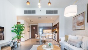 A modern living room with a sofa, coffee table, and a dining area with chairs and a table. - Charming 1BR Apartment in Creek Edge Tower 1, Dubai Creek Harbor by Deluxe Holiday Homes (Dubai)