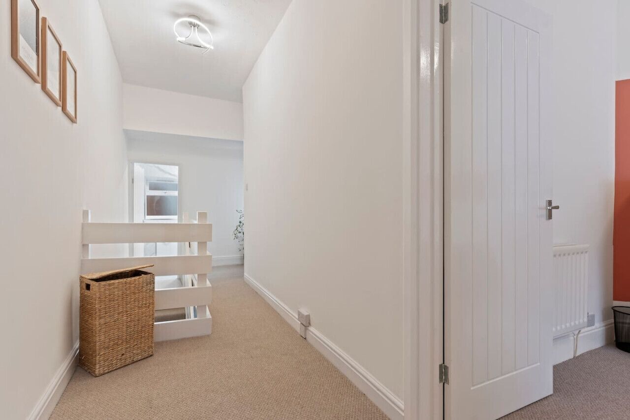 A hallway with a white door, a white bench, and a wicker basket.