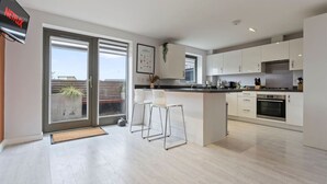 A modern kitchen with a large island, bar stools, and a built-in TV.