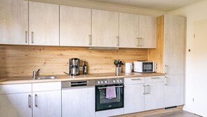 A modern kitchen with light wood cabinets, stainless steel appliances, and a wooden countertop. - Holiday Home Tidenkieker (Nordstrand)