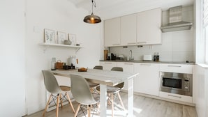 A modern kitchen with white cabinetry, a stainless steel range hood, and a built-in microwave. - Holiday Home in Hygge Style (Ouddorp)