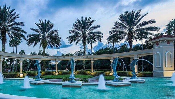 Een zwembadgedeelte met een fontein, palmbomen en een gazebo met de tekst 'Emerald Isle'.