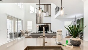 Une cuisine moderne dotée d’un îlot central, d’un four encastré et d’une grande fenêtre donnant sur l’espace de vie.