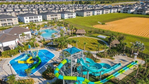 Un parc aquatique doté de plusieurs piscines et de toboggans, entouré d’immeubles d’habitation.