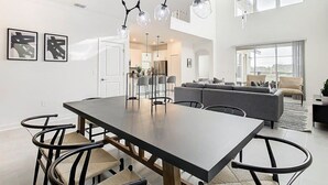 Un espace de restauration moderne avec une longue table, des chaises noires et un lustre original.