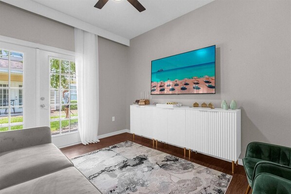 A modern living room with a large window, a white radiator, a green armchair, and a painting of a beach scene.