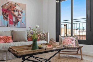 Un salon comprenant un canapé, une table basse avec un plateau, un fauteuil et une grande fenêtre donnant sur un beau paysage.