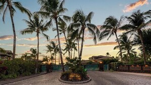 A paved entrance with palm trees and a sign reading "Halimai Kai".