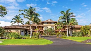 A multi-story hotel with a central courtyard, surrounded by palm trees and lush greenery.