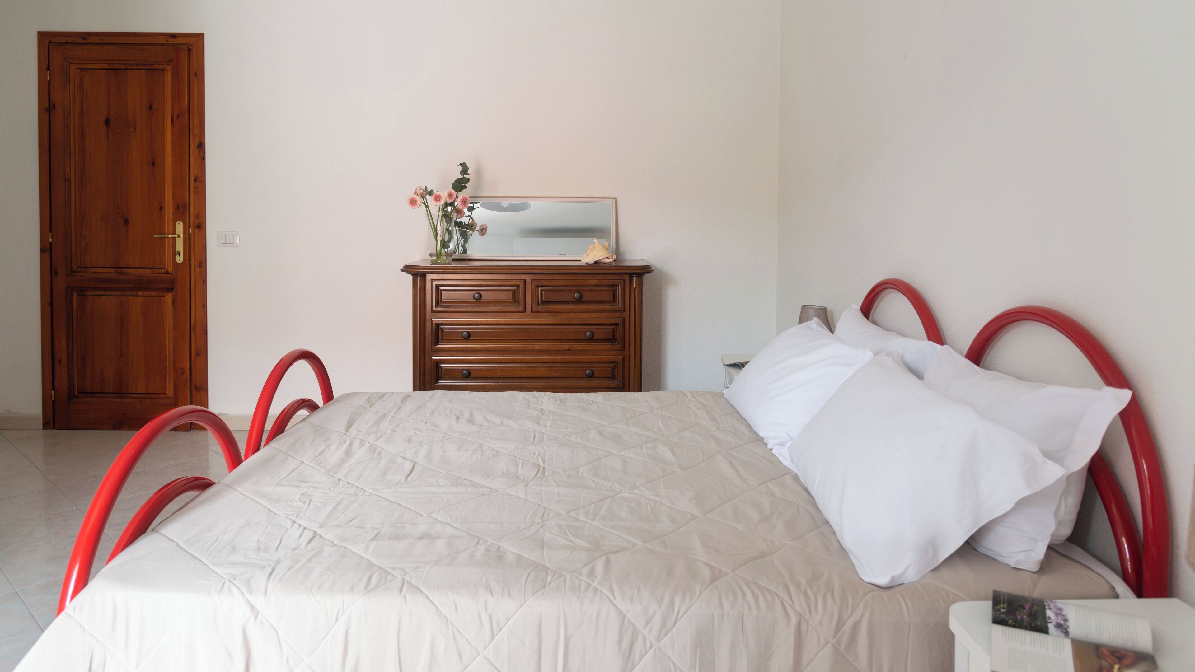 A bedroom with a bed, a dresser, and a door.