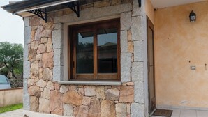Fachada de piedra con una ventana de madera y un toldo metálico.