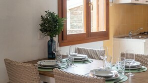 Una mesa de comedor dispuesta con platos, vasos y un florero con plantas verdes.