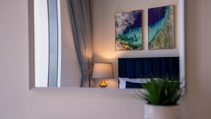 A bedroom with a bed, a bedside lamp, a window with curtains, and two wall-mounted paintings. - One Bedroom Near Dubai Wheel & JBR by Belvilla (Dubai)
