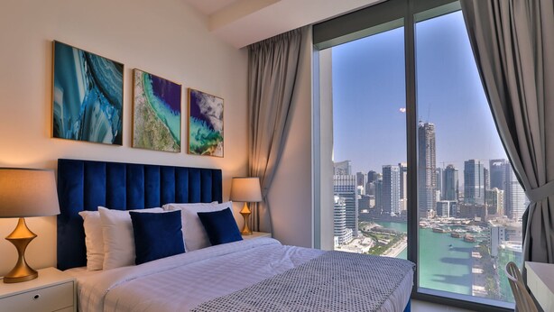 A modern bedroom with a large bed, two bedside tables, and a city view. - One Bedroom Near Dubai Wheel & JBR by Belvilla (Dubai)