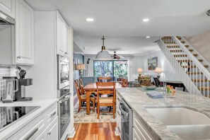 Una cocina moderna con comedor, una isla grande y una escalera que sube a un altillo.