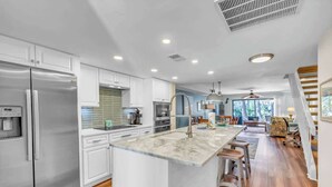 Een moderne keuken met een centraal eiland, roestvrijstalen apparatuur en een eetgedeelte met barstoelen.