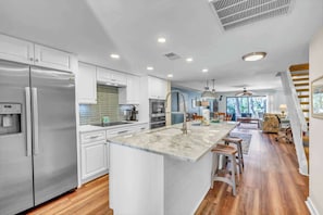 A modern kitchen with a central island, stainless steel appliances, and a dining area with bar stools.