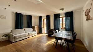 Uma sala moderna com sofá, mesa de jantar, cadeiras e uma pequena mesa lateral.