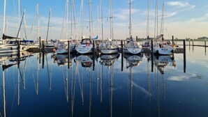 A marina with multiple sailboats docked at calm water. - Holiday Home Apartment - East (Grossenbrode)