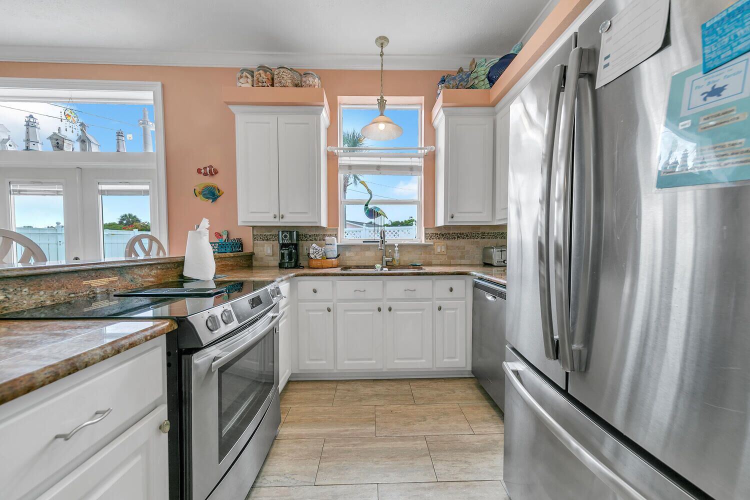 A kitchen with white cabinets, stainless steel appliances, and a window with a view of the sky.