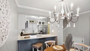 Une cuisine moderne dotée d’un îlot central, de meubles blancs et d’un lustre.