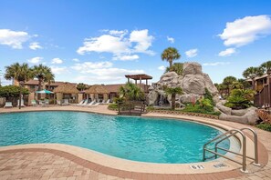 A swimming pool with lounge chairs and a rock formation.