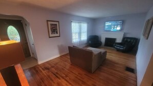 A living room with wooden flooring, a sofa, a chair, and a television on a stand. - Do Not Book, VRBO sucks and won't let me delete this house I do not own anymore! (New Albany)