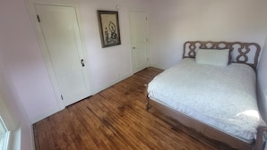 A bedroom with a wooden floor, a bed with a white bedspread, two white doors, and a framed picture on the wall. - Do Not Book, VRBO sucks and won't let me delete this house I do not own anymore! (New Albany)