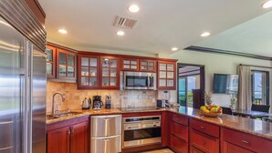 A modern kitchen with stainless steel appliances, wooden cabinetry, and a view to the outside.
