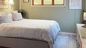 Ein Schlafzimmer mit Bett, Nachttisch, Lampe, Fenster und einer Karte an der Wand.