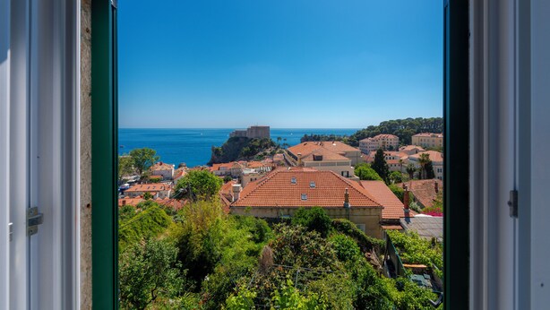 A coastal town with buildings, a prominent castle-like structure, and a clear blue sky.