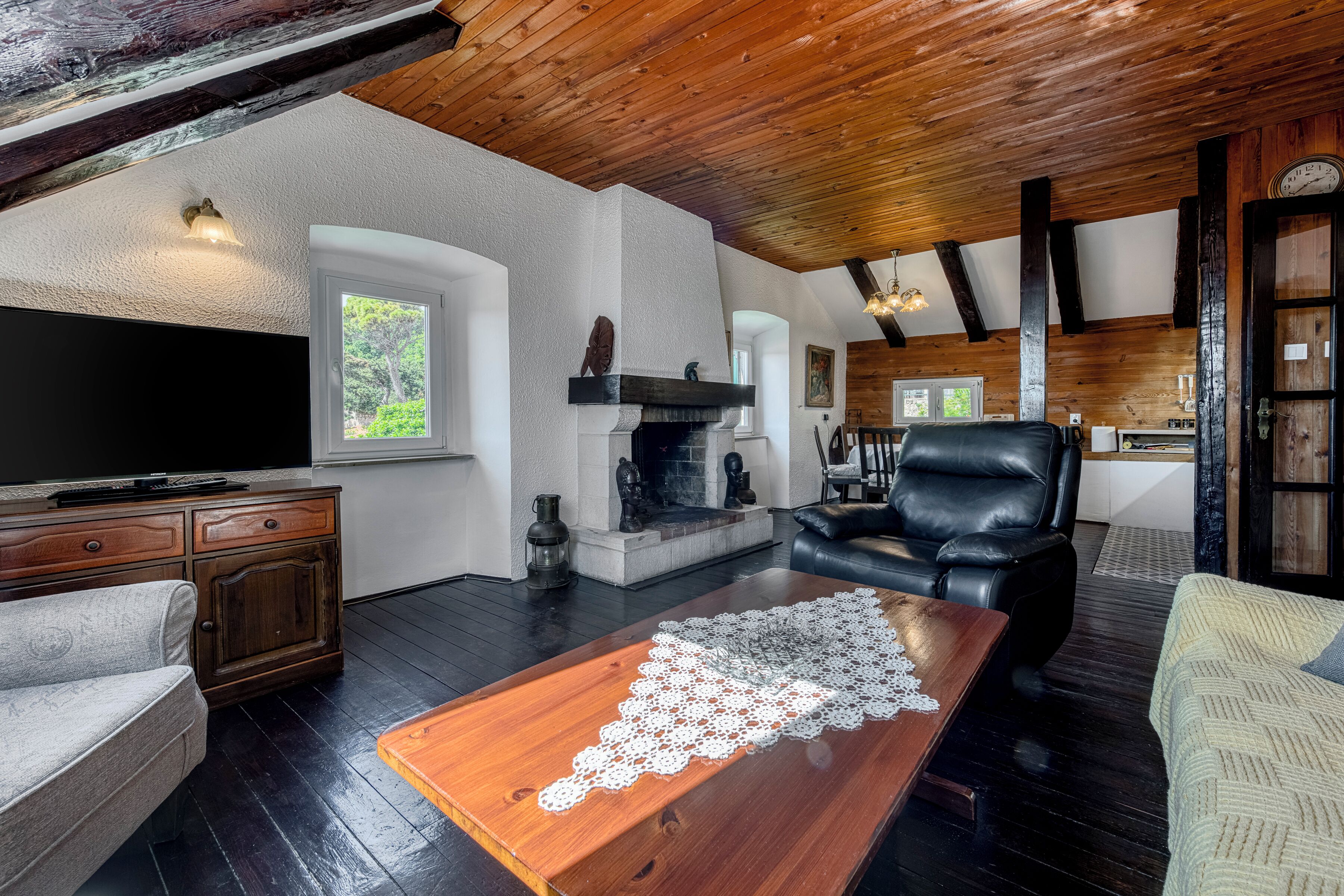 Una sala de estar acogedora con chimenea, sofá de cuero y televisor.