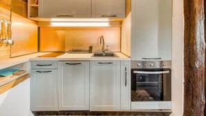 A compact kitchen with white cabinets, a built-in oven, and a microwave.